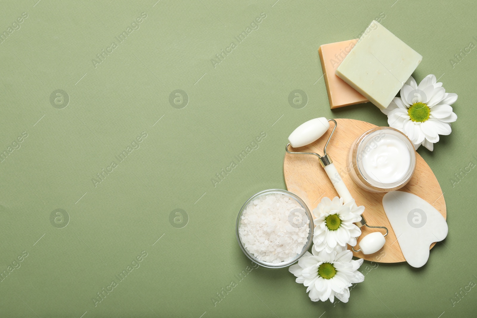 Photo of Flat lay composition with face roller and gua sha tool on green background, space for text