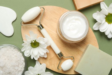 Photo of Flat lay composition with face roller and gua sha tool on green background