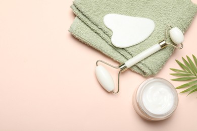 Photo of Face roller, gua sha tool, towel, cosmetic product and palm leaf on beige background, flat lay. Space for text