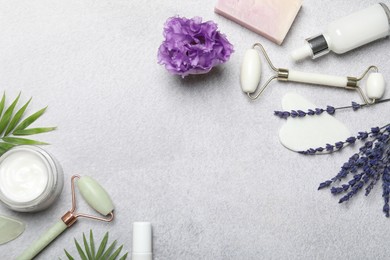 Photo of Flat lay composition with face rollers and gua sha tool on gray background, space for text