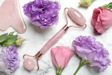 Photo of Face roller, gua sha tool and beautiful flowers on white marble background, flat lay