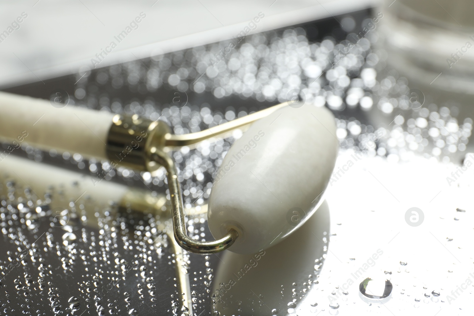 Photo of Face roller on mirror with water drops, closeup