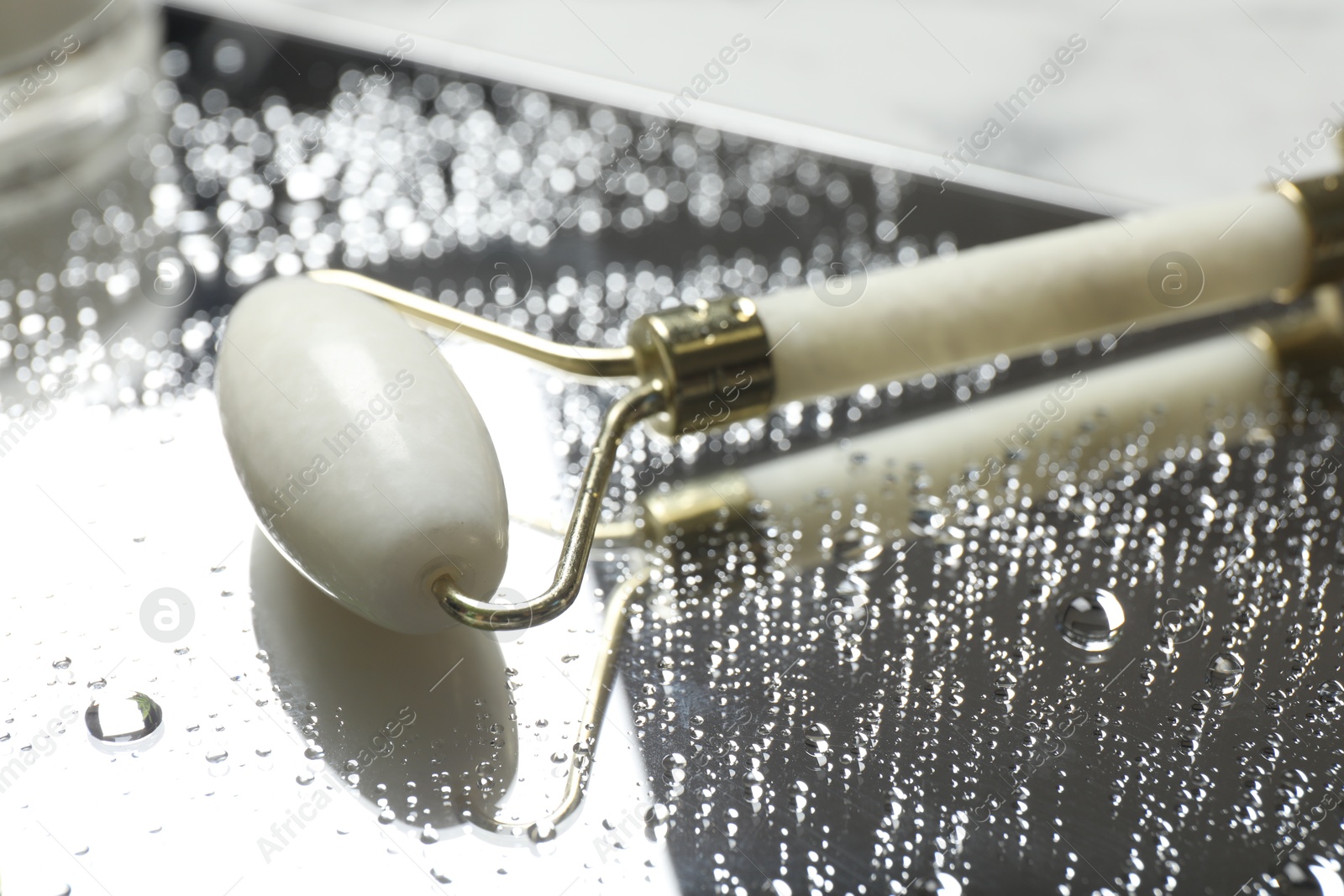 Photo of Face roller on mirror with water drops, closeup