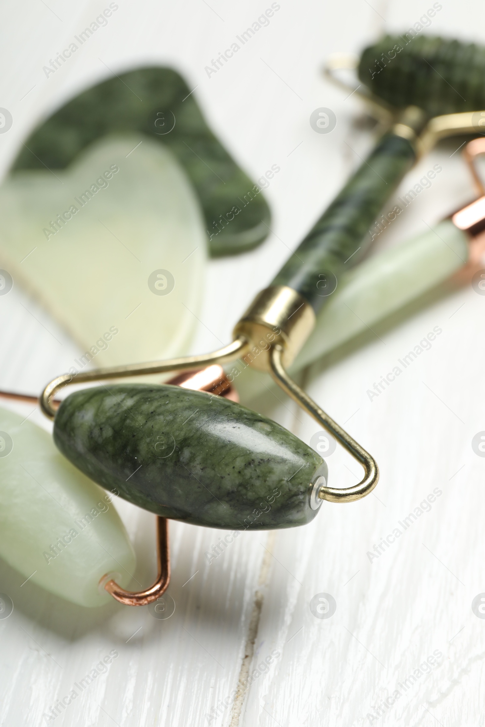 Photo of Face rollers on white wooden background, closeup