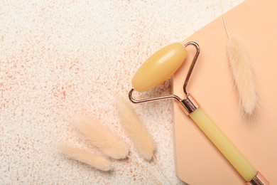 Photo of Face roller and dry spikes on beige textured background, flat lay. Space for text