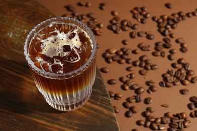 Refreshing espresso tonic drink and coffee beans on brown background, closeup