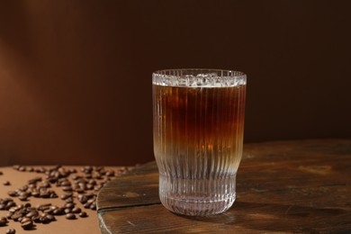 Refreshing espresso tonic drink on wooden table against brown background