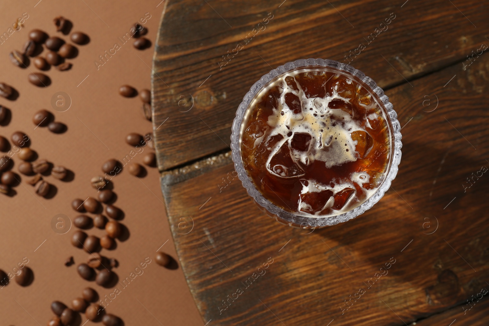 Photo of Refreshing espresso tonic drink and coffee beans on brown background, flat lay