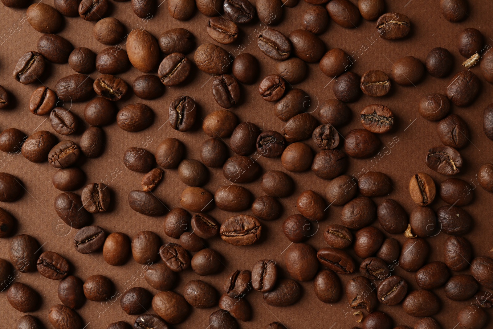 Photo of Many coffee beans on brown background, top view