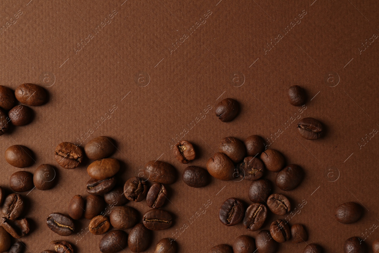 Photo of Many coffee beans on brown background, top view