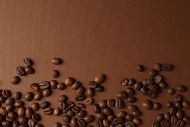 Many coffee beans on brown background, top view. Space for text