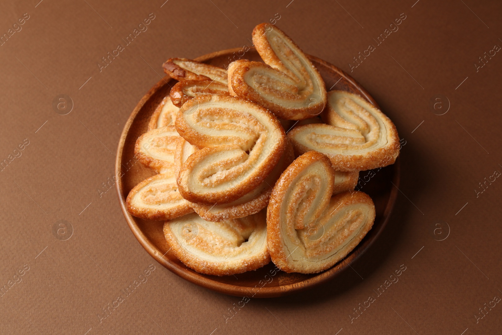 Photo of Tasty french palmier cookies on brown background, closeup