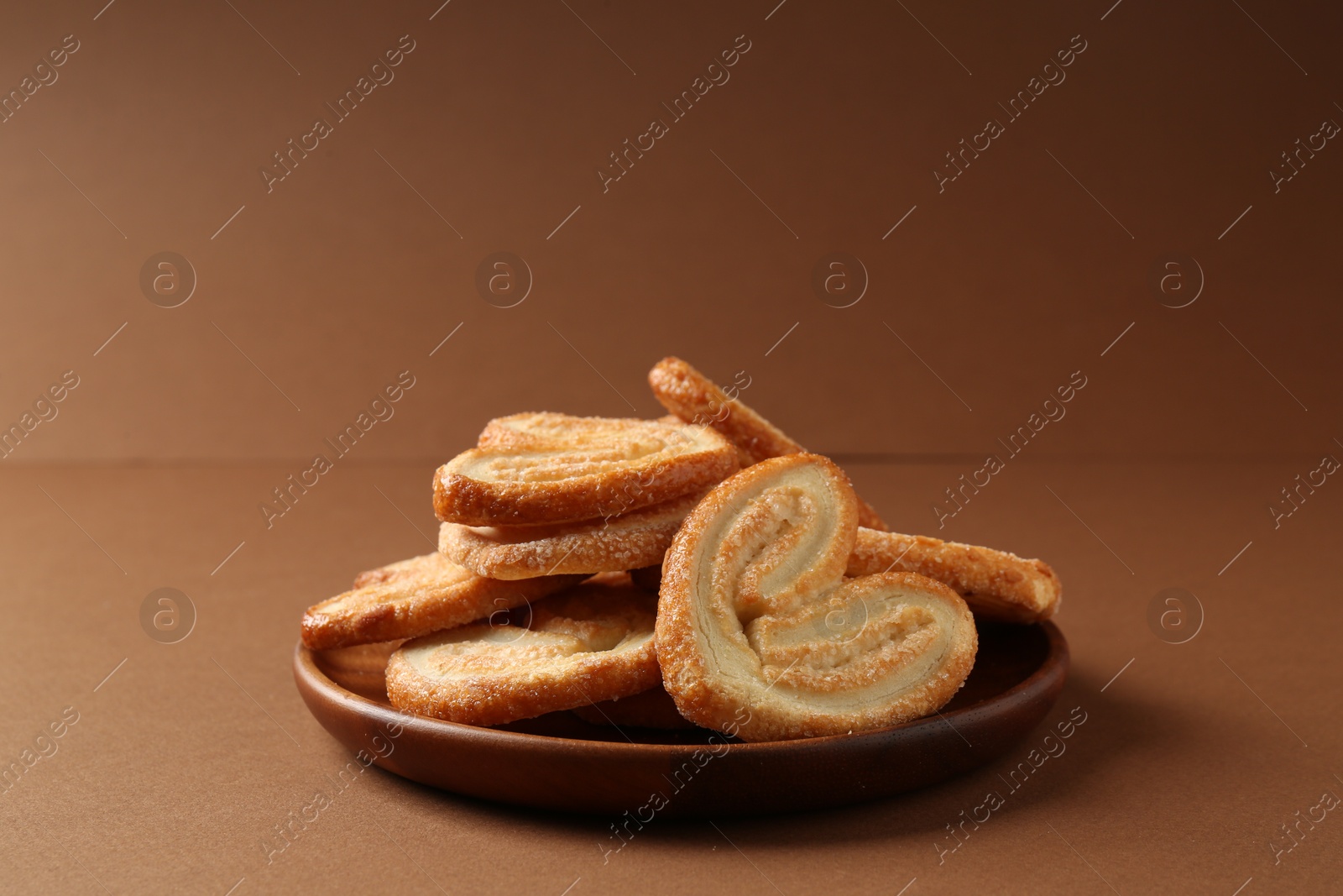 Photo of Tasty french palmier cookies on brown background