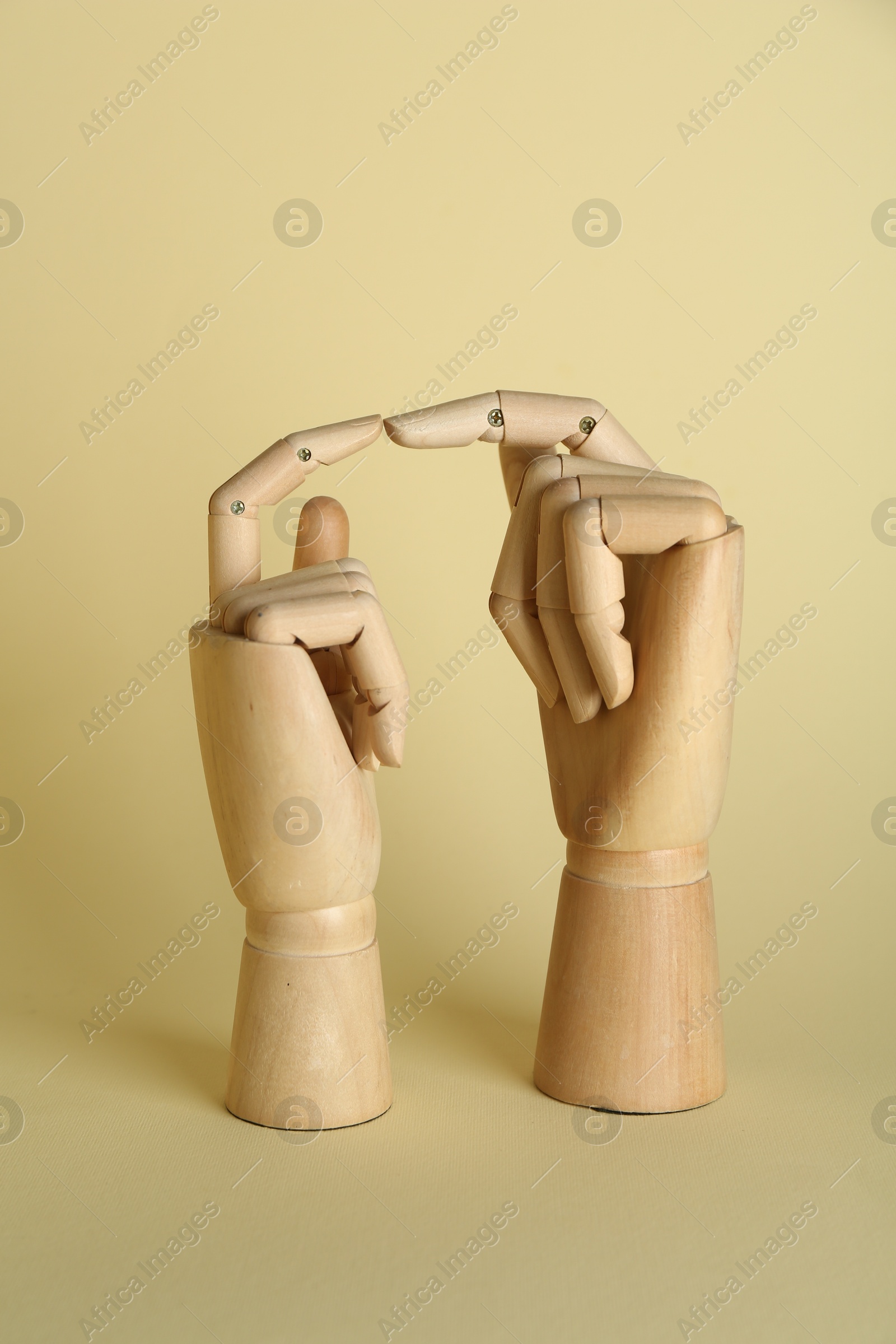 Photo of Two wooden mannequin hands on beige background