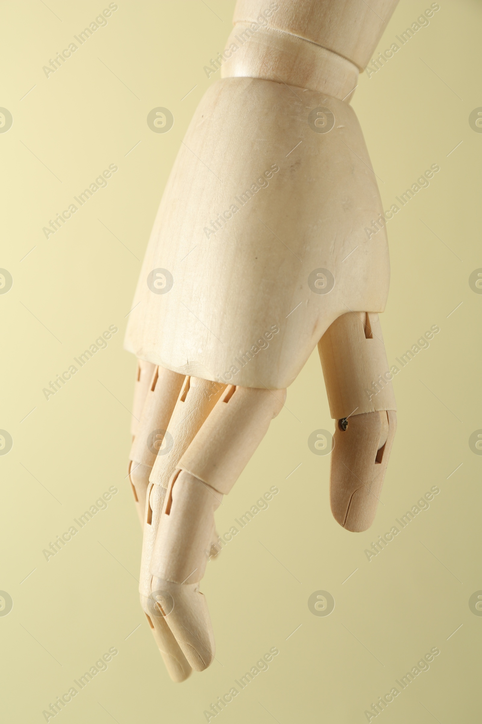 Photo of Wooden mannequin hand on beige background, closeup