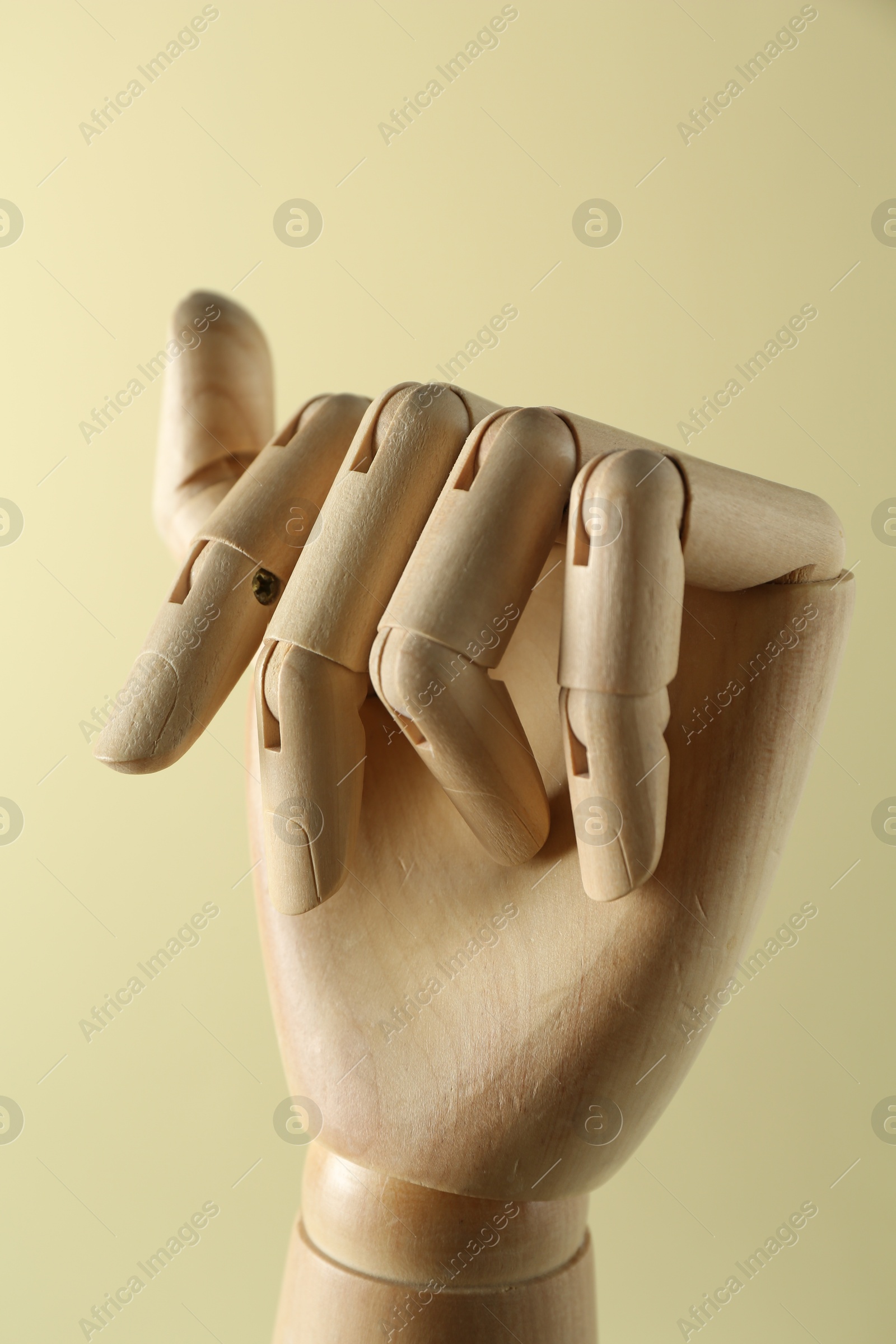 Photo of Wooden mannequin hand on beige background, closeup