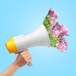 Image of Woman holding loudspeaker with sticking out of it peony flowers on light blue background, closeup