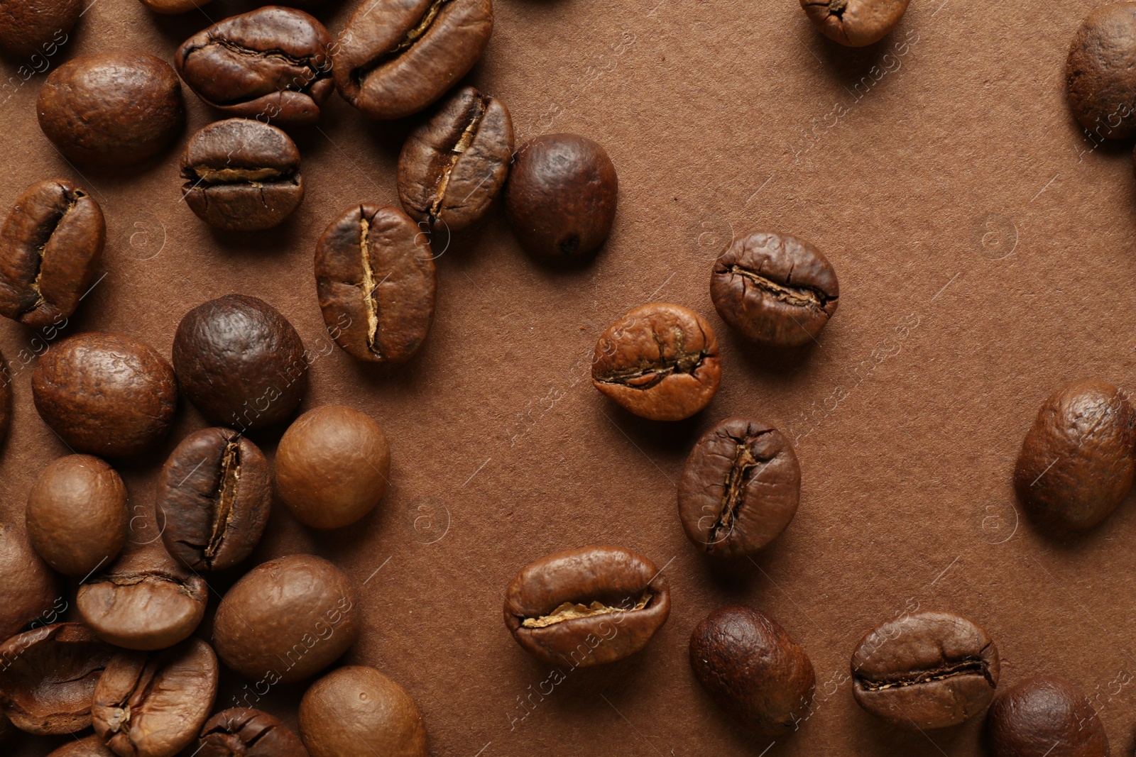 Photo of Many coffee beans on brown background, top view