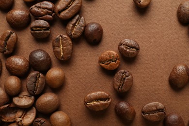 Many coffee beans on brown background, top view