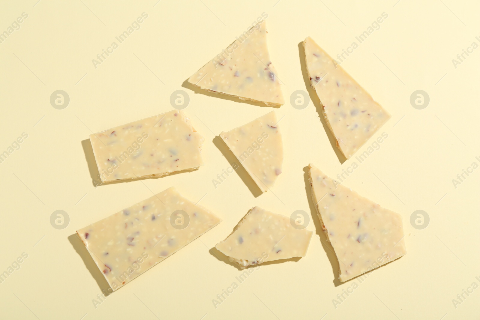 Photo of Pieces of tasty white chocolate on beige background, top view