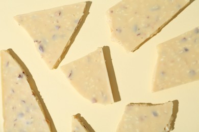 Photo of Pieces of tasty white chocolate on beige background, top view