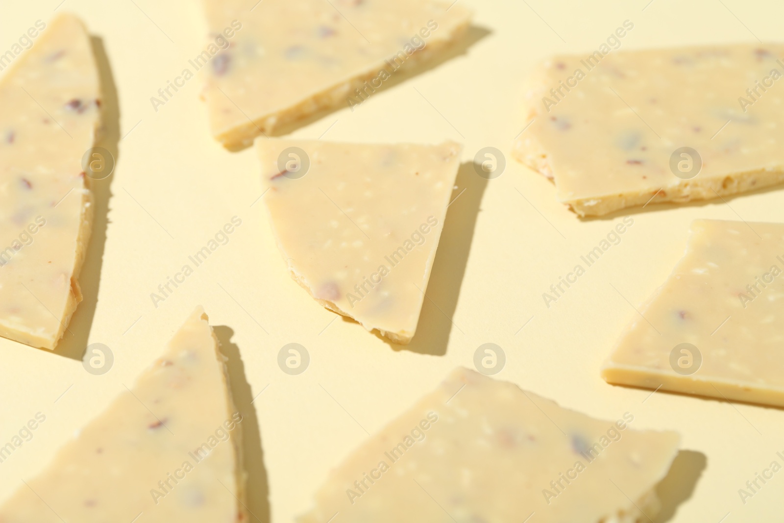 Photo of Pieces of tasty white chocolate on beige background, closeup