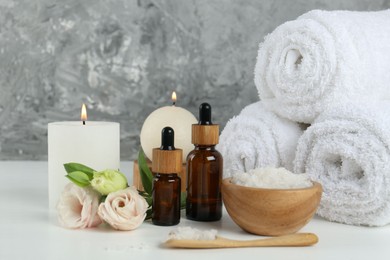 Spa composition with cosmetic products and towels on white table