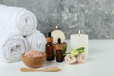 Spa composition with cosmetic products and towels on white table