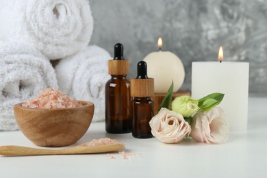 Spa composition with cosmetic products and towels on white table