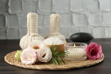 Massage bags, spa stones, sea salt, burning candle and flowers on wooden table