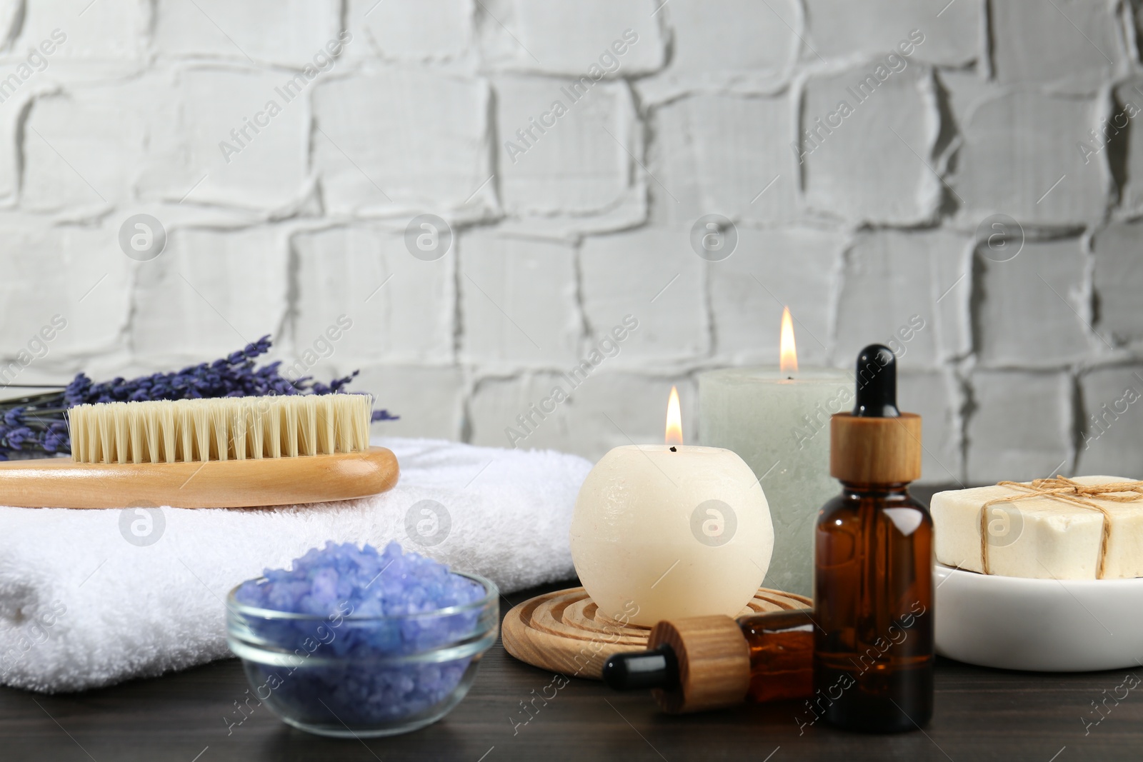 Photo of Spa treatment. Composition with cosmetic products and towel on wooden table