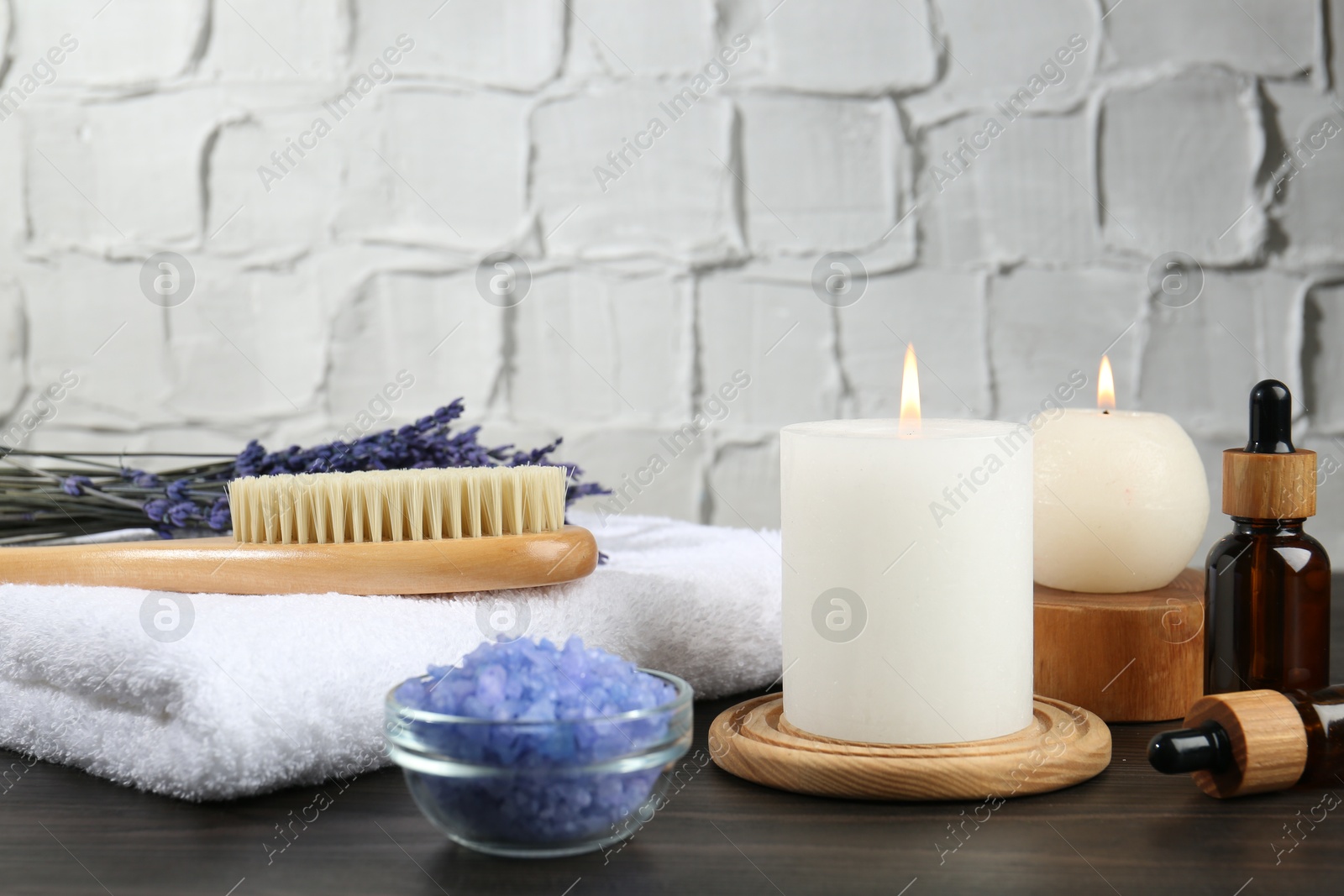 Photo of Spa treatment. Composition with cosmetic products and towel on wooden table