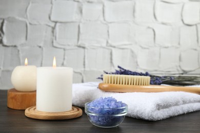 Photo of Spa treatment. Composition with burning candles and towel on wooden table