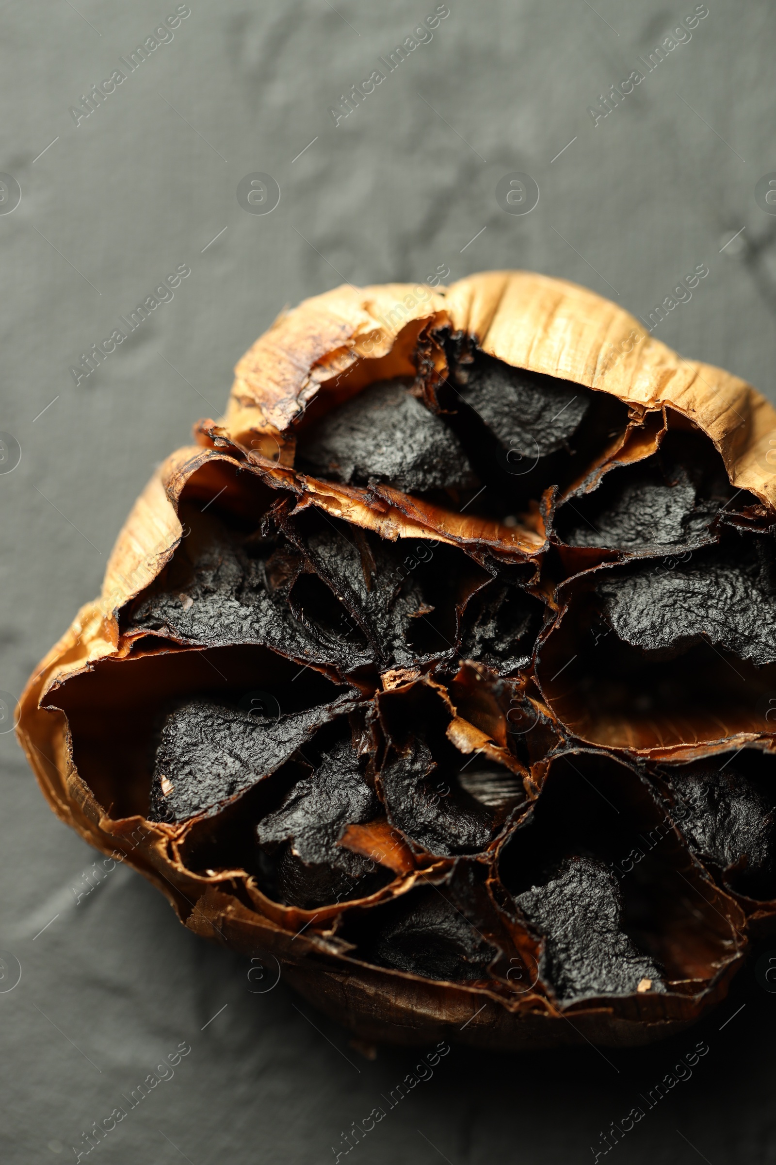 Photo of Bulb of aged garlic on black table, top view