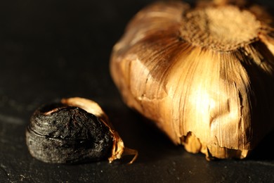 Photo of Bulb of aged garlic on black table, closeup