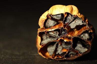 Bulb of aged garlic on black table, closeup