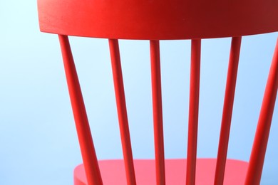 Red wooden chair on light blue background, closeup