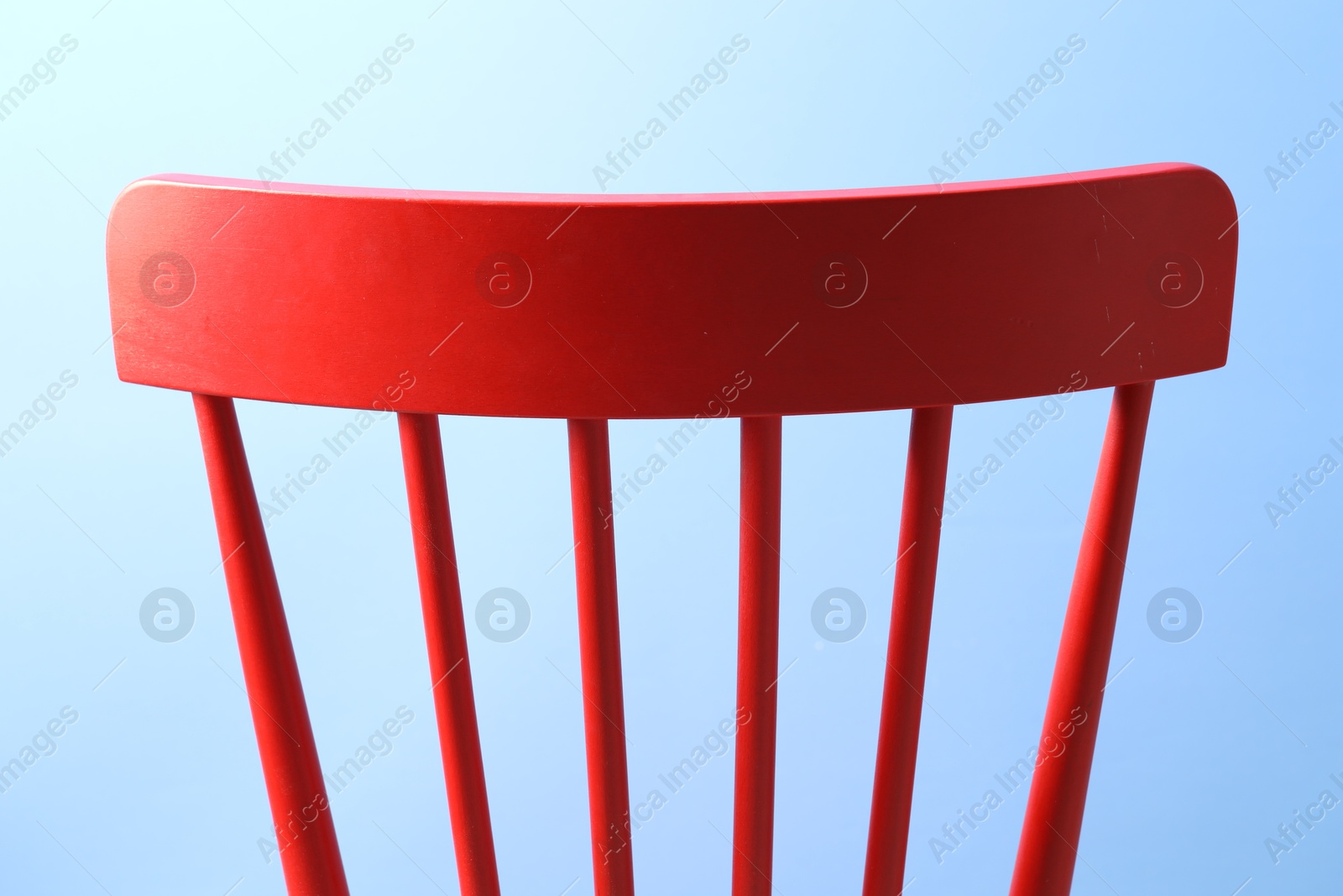 Photo of Red wooden chair on light blue background, closeup