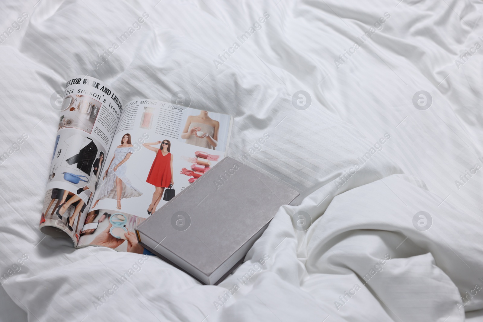 Photo of Magazine and book on bed with clean linens indoors