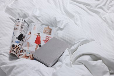 Magazine and book on bed with clean linens indoors