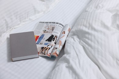 Photo of Magazine and book on bed with clean linens indoors