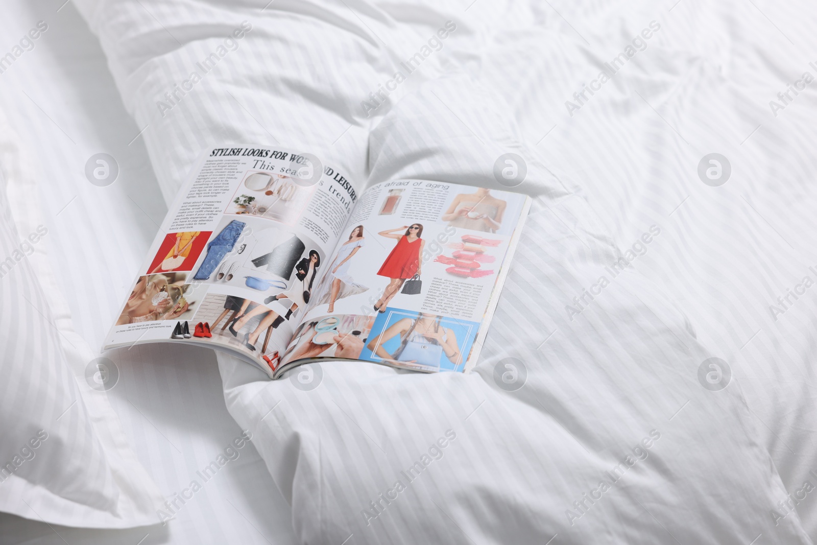 Photo of Open magazine on bed with clean linens indoors