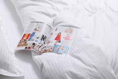 Open magazine on bed with clean linens indoors