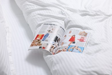 Photo of Open magazine on bed with clean linens indoors