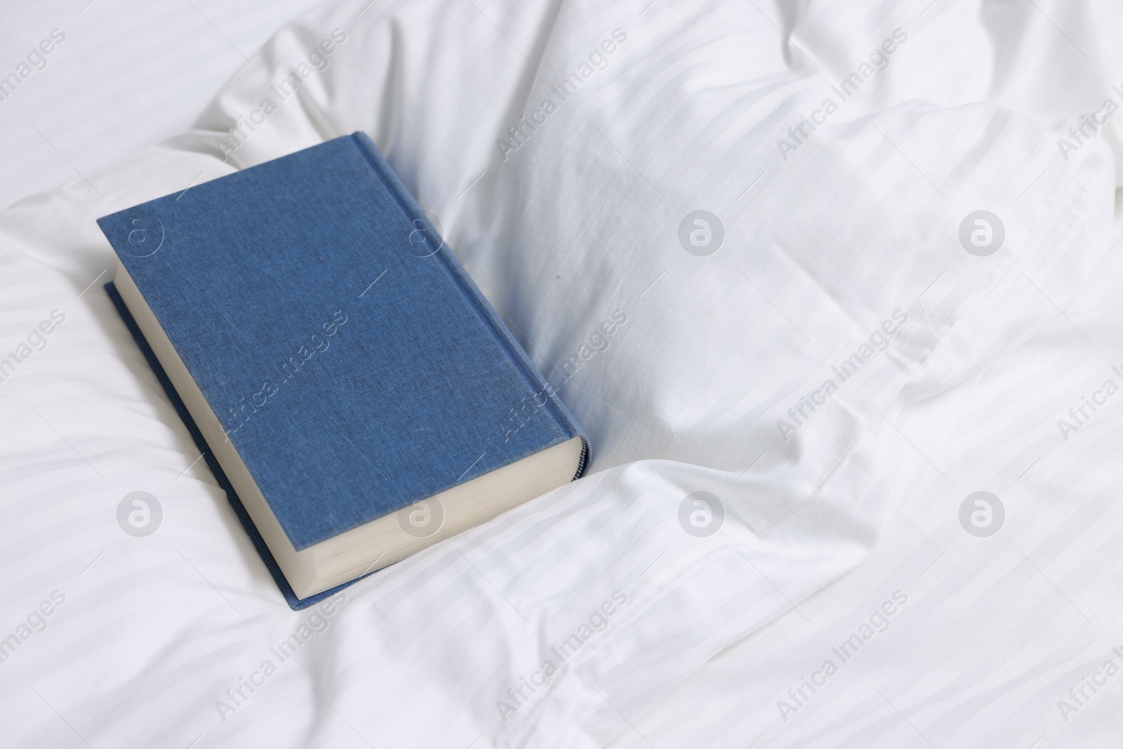 Photo of One book on bed with clean linens indoors, space for text