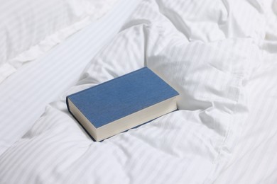 Photo of One book on bed with clean linens indoors