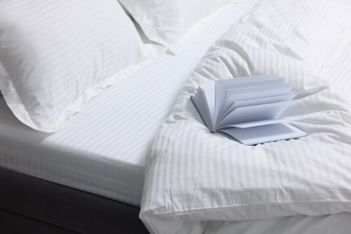 Open book on bed with clean linens indoors