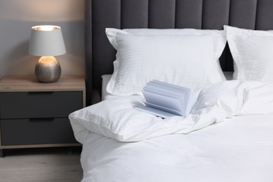 Photo of Open book on bed with clean linens indoors