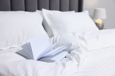 Photo of Open book on bed with clean linens indoors