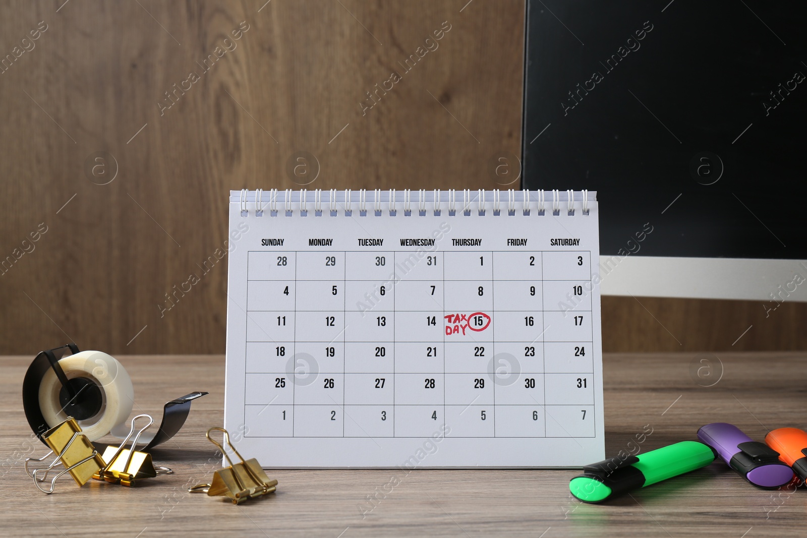 Photo of Timetable. Monthly planner, stationery and computer on wooden table